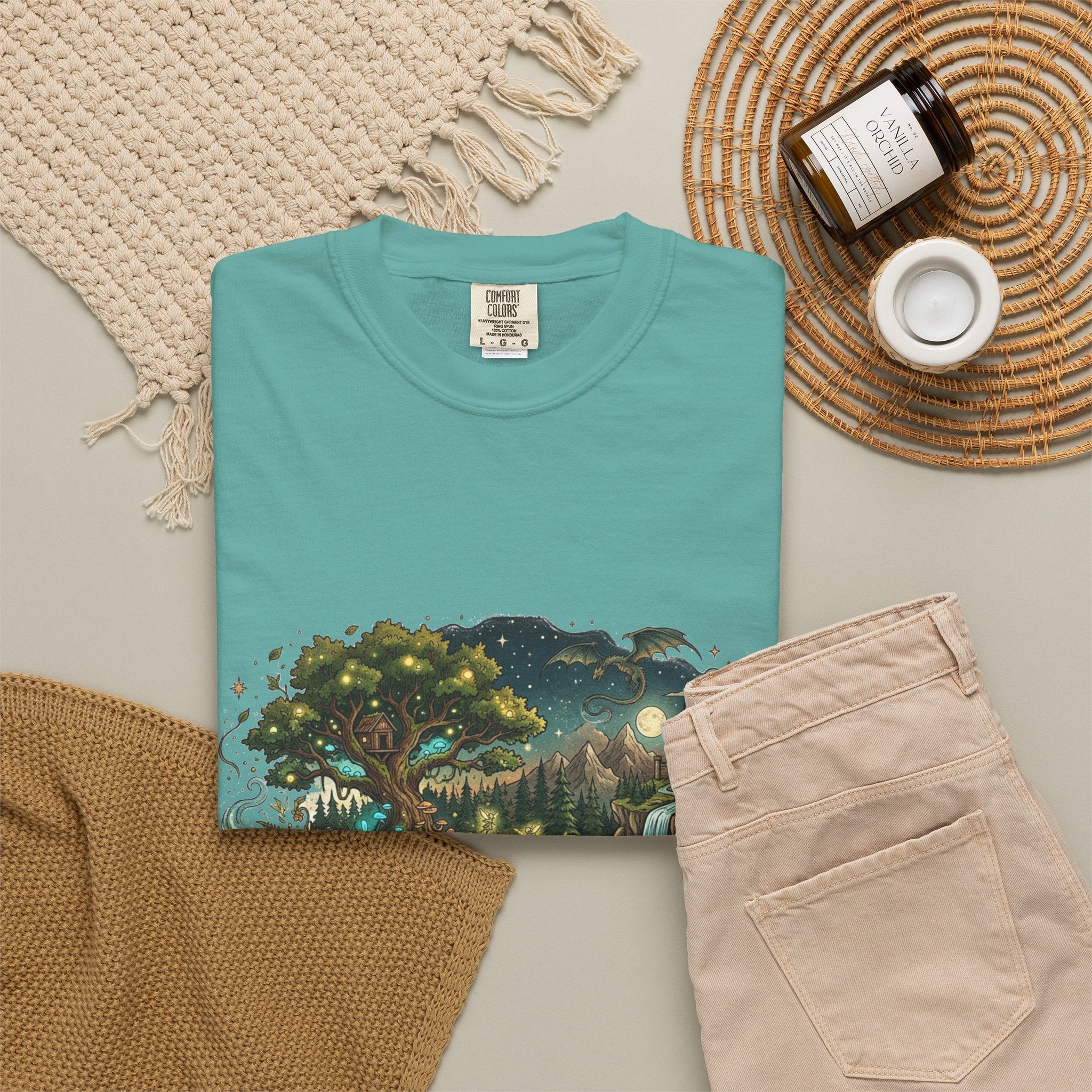 Fantasy book lover tee featuring an enchanted forest, waterfall, and castle emerging from an open book.