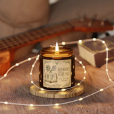 A lit amber glass jar candle with a cream label reading &