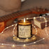 A lit amber glass jar candle with a cream label reading &