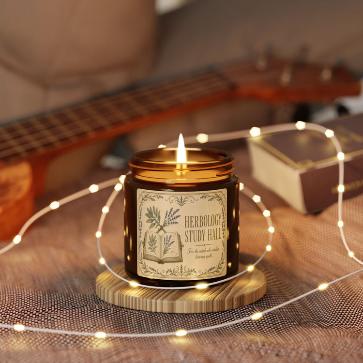 A lit amber glass jar candle with a cream label reading &