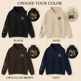 A color selection graphic showing four hoodies labeled BLACK, SAND, CHOCOLATE BROWN, and NAVY, each with a circular inset of a matching hoodie featuring a large vintage train graphic on the front and sleeve. Text at the top reads &