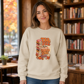 A woman wearing a cream-colored crewneck sweatshirt with a &