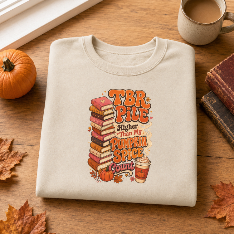 A folded cream-colored t-shirt with a colorful autumn-themed graphic reading &
