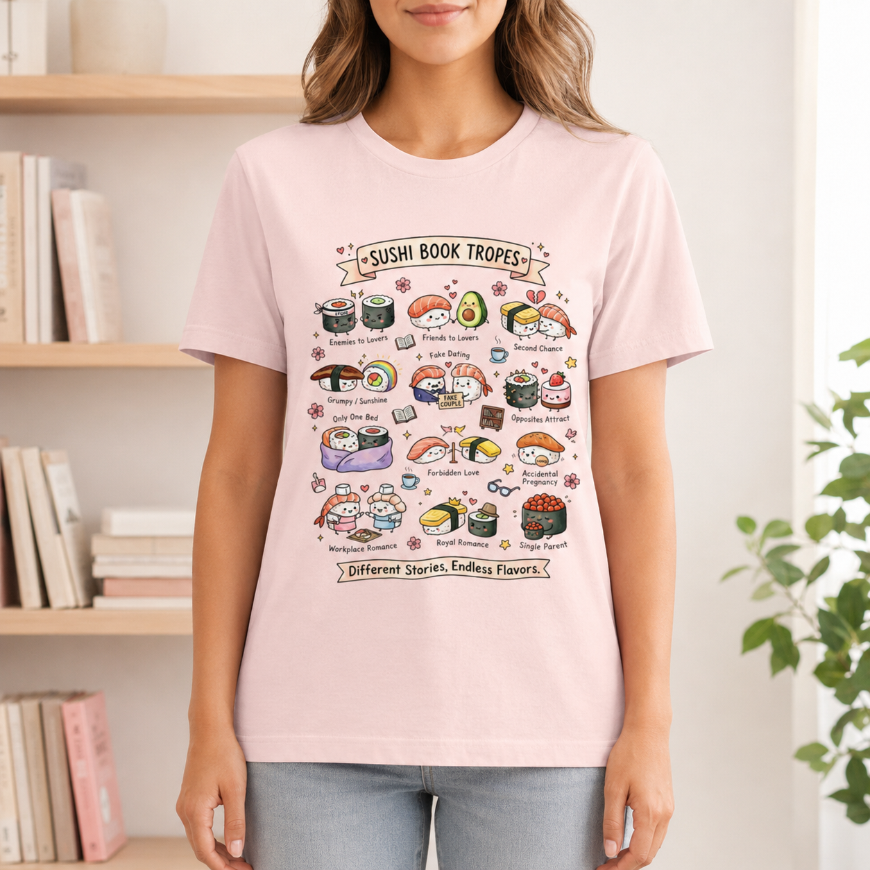 A woman wearing a light pink graphic t-shirt with a colorful cartoon illustration of sushi tropes and cat characters. The background shows a softly blurred indoor setting with bookshelves and a plant.