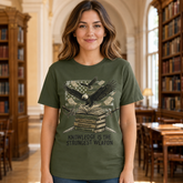 A woman wearing an olive green graphic t-shirt in a library setting. The t-shirt features a graphic of an eagle over stacked books with an American flag background and the text &