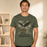 A man wearing an olive green graphic t-shirt with a design of an eagle over books and a dollar bill, with the text &