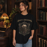 A woman wearing a black graphic t-shirt with the text &