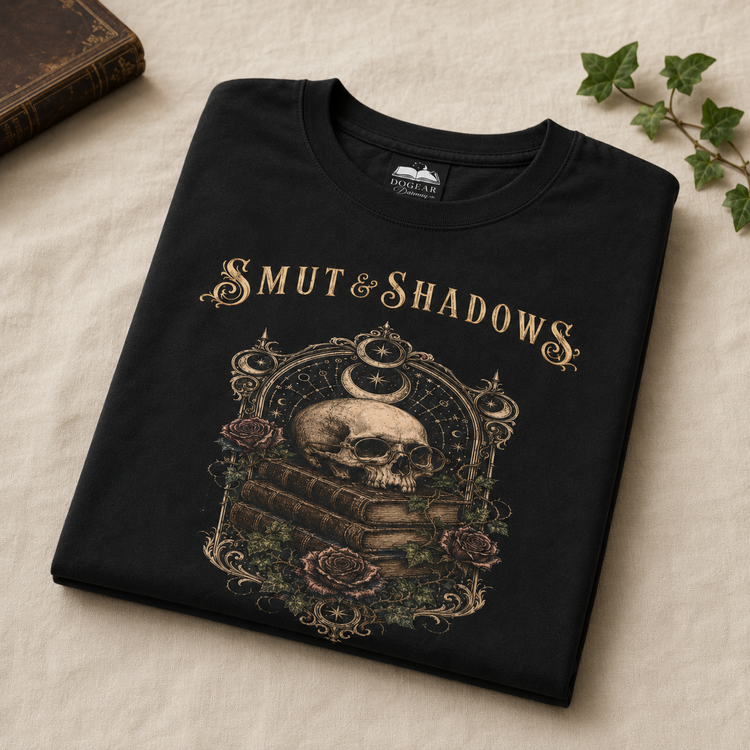 A folded black t-shirt with a gothic-style graphic print featuring a skull on stacked books, roses, and the text &