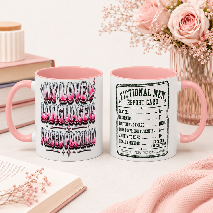 Two white ceramic mugs with pink interiors and pink handles are displayed on a light surface with books and pink flowers in the background. The left mug has pink, black, and gray graffiti-style text reading &