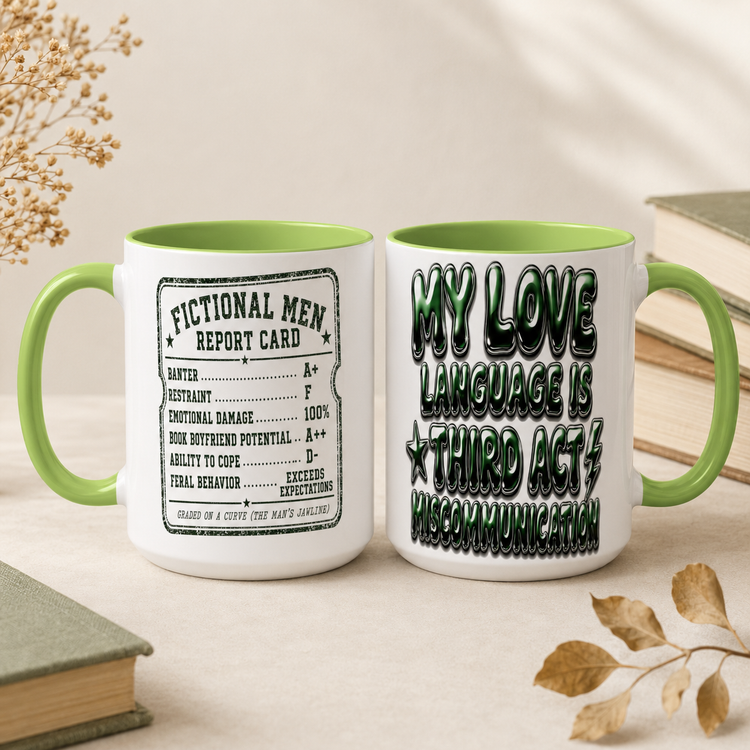 Two white ceramic mugs with green handles and interiors, styled on a beige tabletop with books and dried leaves. One mug shows a vintage-style report card design reading &