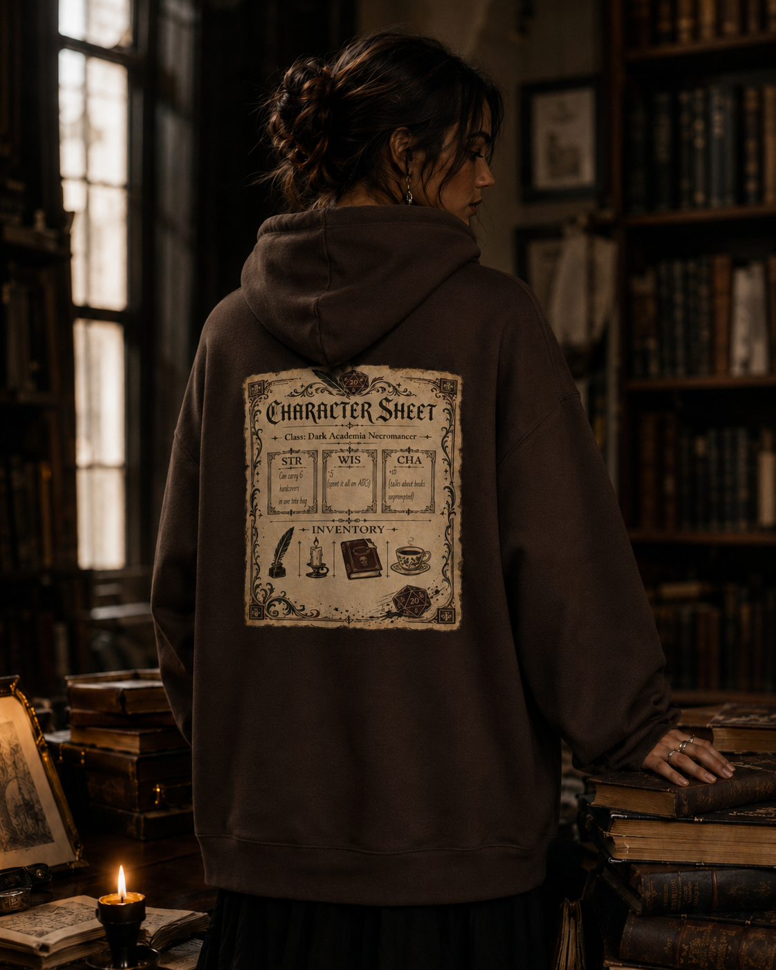 A person standing in a dimly lit library or study, shown from the back wearing a dark brown hoodie with a large vintage-style character sheet graphic printed on the back.