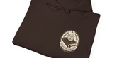 A dark brown folded hoodie on a white background, featuring a circular graphic on the front with a book, a dice icon, and the text &