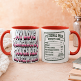 Two white ceramic mugs with red handles and interiors are shown side by side on a beige tabletop. The left mug has large pink, black, and white text reading &