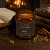 A personalized amber glass jar candle with a black lid, labeled &