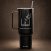 A black insulated travel tumbler with a handle and clear lid, featuring a white laser-engraved design of an open book with a sword and the words &