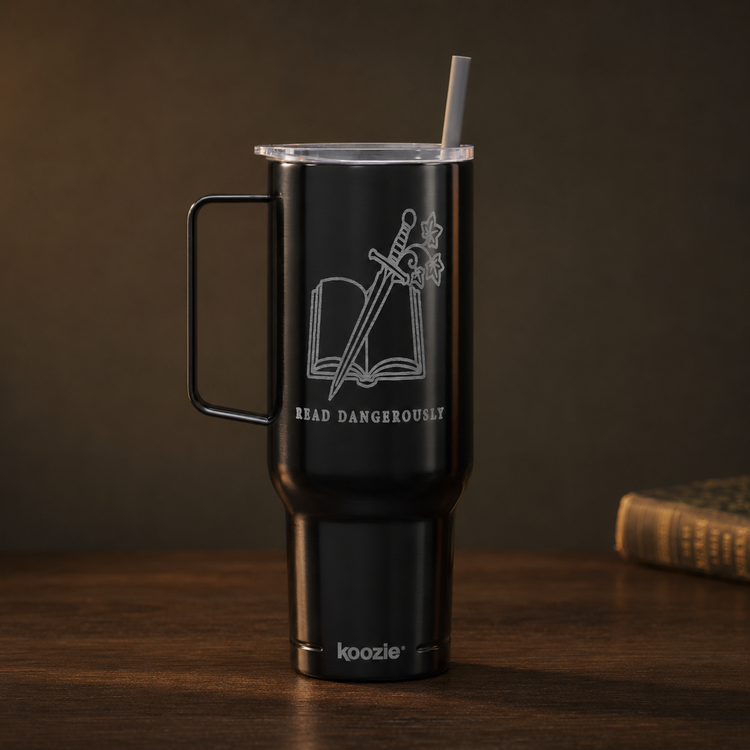 A matte black insulated tumbler with a handle, clear lid, and straw, featuring a white laser-engraved design of an open book and sword with the text &