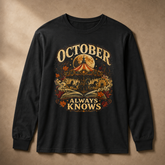 A black long-sleeve t-shirt with a detailed graphic print on the front, featuring a carousel, autumn leaves, an open book, and a full moon with the text &
