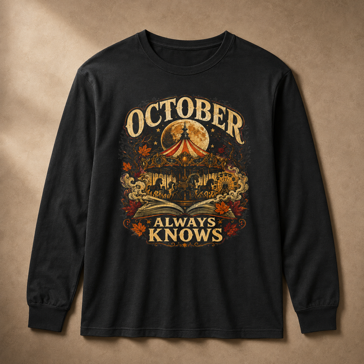 A black long-sleeve t-shirt with a detailed graphic print on the front, featuring a carousel, autumn leaves, an open book, and a full moon with the text &