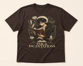 A dark brown short-sleeve t-shirt with a detailed fantasy graphic of a character reading a book, surrounded by magical symbols, with the text &