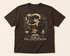 A dark brown short-sleeve t-shirt with a detailed fantasy graphic of a character reading a book, surrounded by magical symbols, with the text &