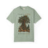 A sage green short-sleeve t-shirt with a graphic of a tree and an open book with a bird, featuring the text &