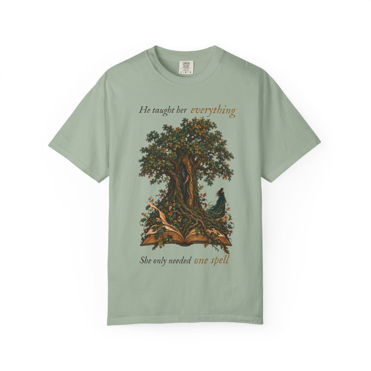 A sage green short-sleeve t-shirt with a graphic of a tree and an open book with a bird, featuring the text &