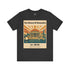 A dark heather gray t-shirt with a vintage-style graphic print on the front. The graphic features a beige background with retro illustrations of the Library of Alexandria, including columns, a sunburst, sailboats, and a lighthouse, with text reading &