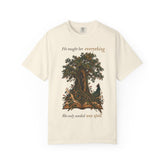 An off-white short-sleeve t-shirt with a graphic of a tree growing from an open book, accompanied by a peacock. The text reads &